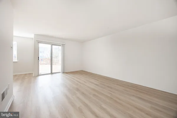 a view of an empty room and wooden floor and a window