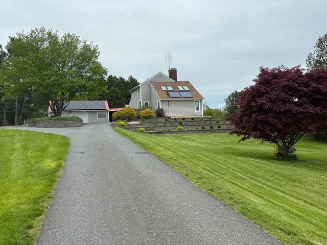 a view of a house with a big yard potted plants and a large tree