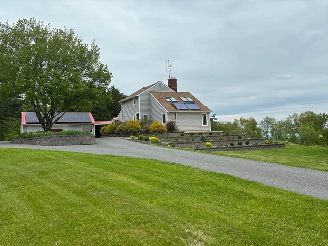 a front view of a house with a garden and trees