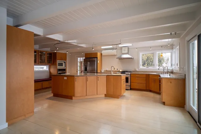 a large kitchen with stainless steel appliances kitchen island granite countertop a refrigerator and a sink