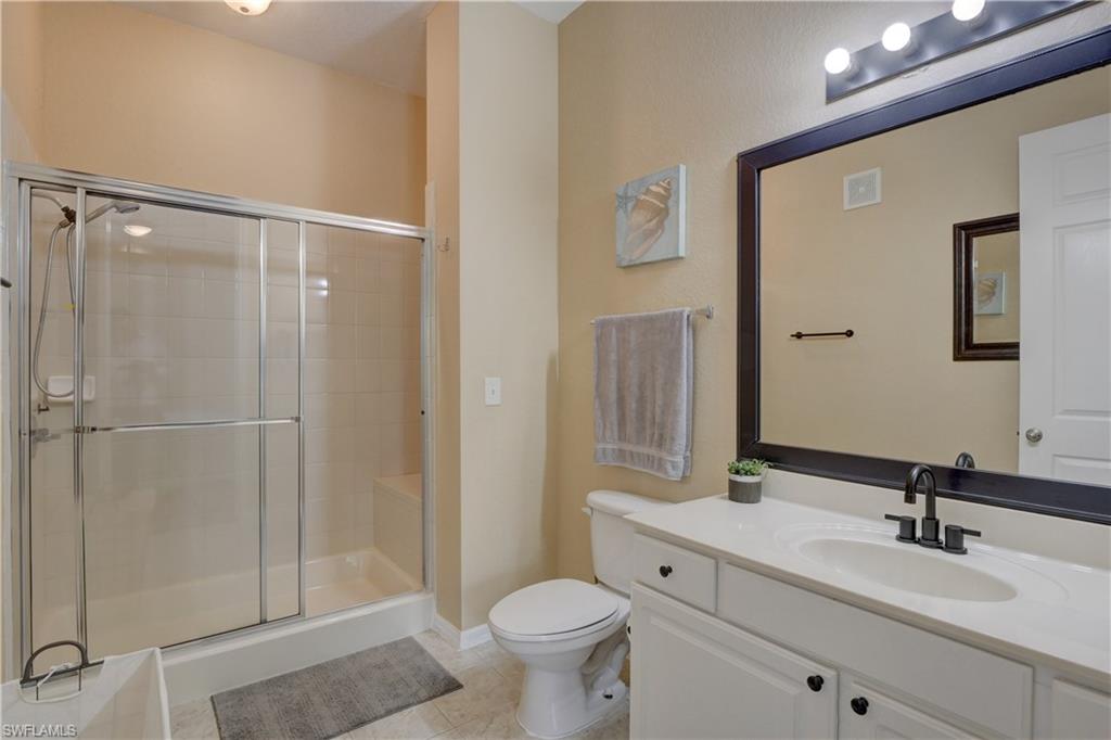 990 Peggy Circle, Unit 404 Naples, FL 34113 - Photo 15 of 26 a bathroom with a sink a toilet a mirror and shower
