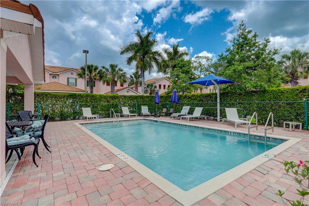 990 Peggy Circle, Unit 404 Naples, FL 34113 - Photo 3 of 26 a view of a swimming pool with a table and chairs under an umbrella