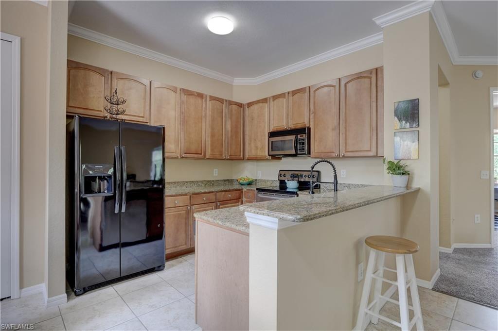990 Peggy Circle, Unit 404 Naples, FL 34113 - Photo 7 of 26 a kitchen with granite countertop a refrigerator and a stove top oven