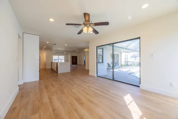 a view of empty room with wooden floor and fan