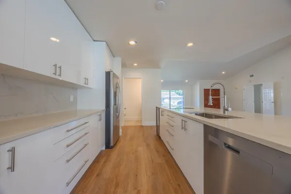 a large kitchen with stainless steel appliances a sink and cabinets