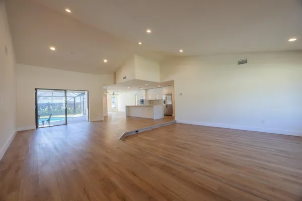 a view of empty room with wooden floor and windows
