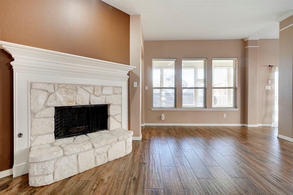 7519 Forest Ridge Trail Sachse, TX 75048 - Photo 15 of 35 a living room with a fireplace and wooden floor