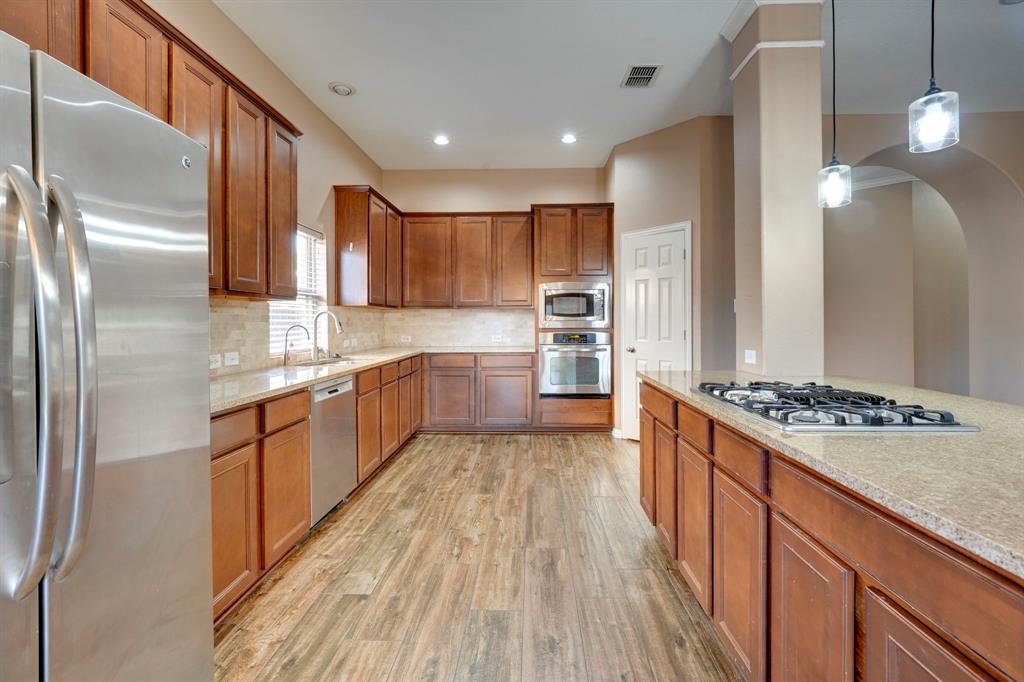7519 Forest Ridge Trail Sachse, TX 75048 - Photo 17 of 35 a large kitchen with stainless steel appliances granite countertop a stove a sink dishwasher and a refrigerator