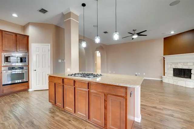 a large kitchen with kitchen island a stove a sink a refrigerator and a wooden floor