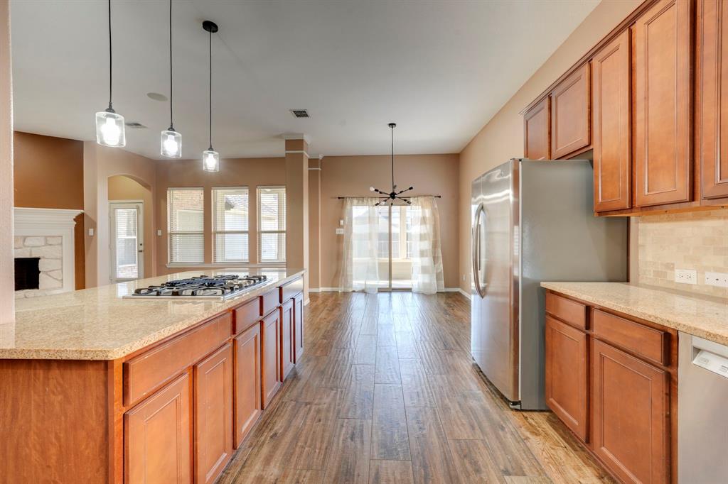 7519 Forest Ridge Trail Sachse, TX 75048 - Photo 19 of 35 a kitchen with stainless steel appliances granite countertop wooden floors stove and refrigerator