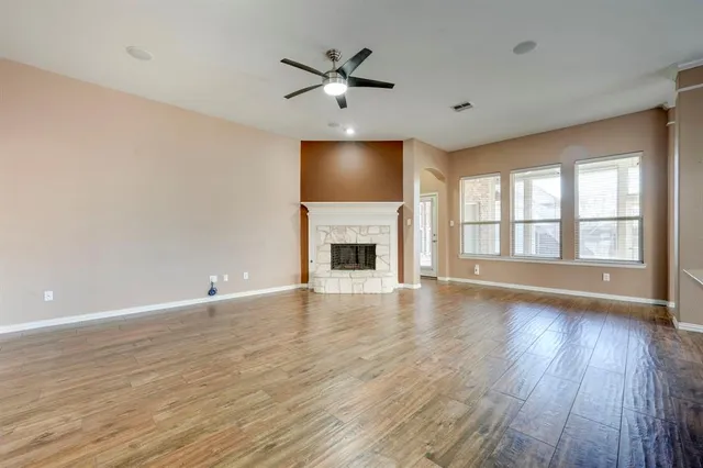 an empty room with wooden floor fireplace and windows