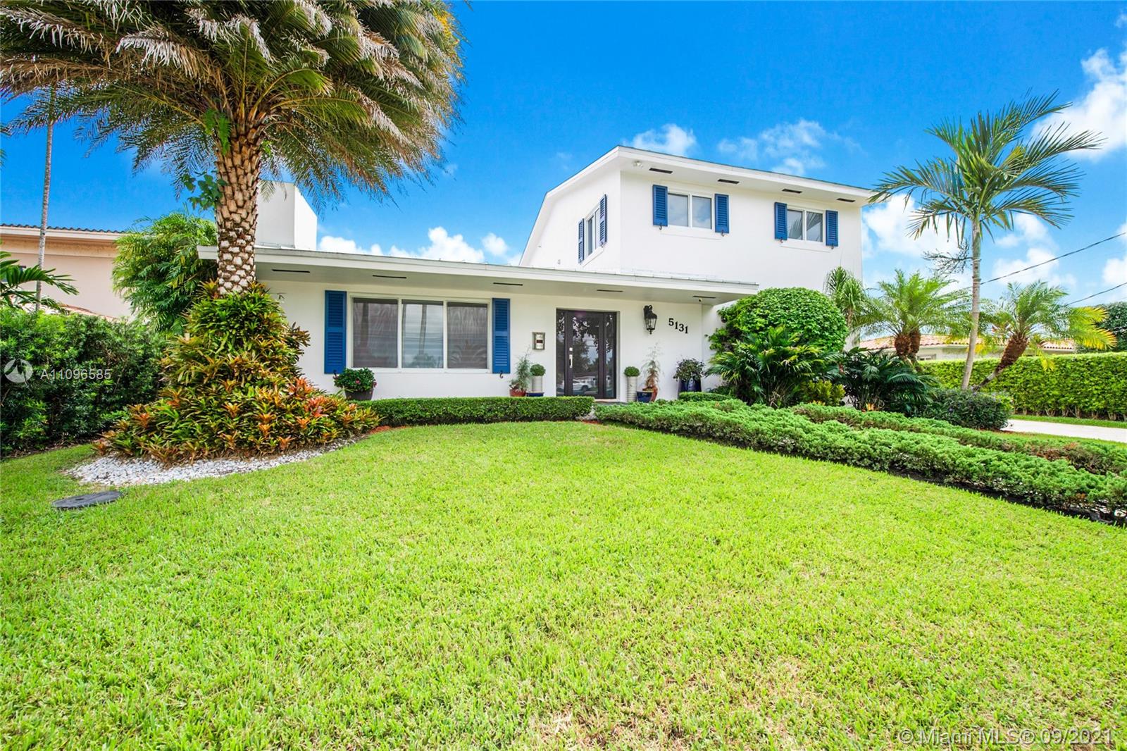 a front view of a house with a yard and palm trees
