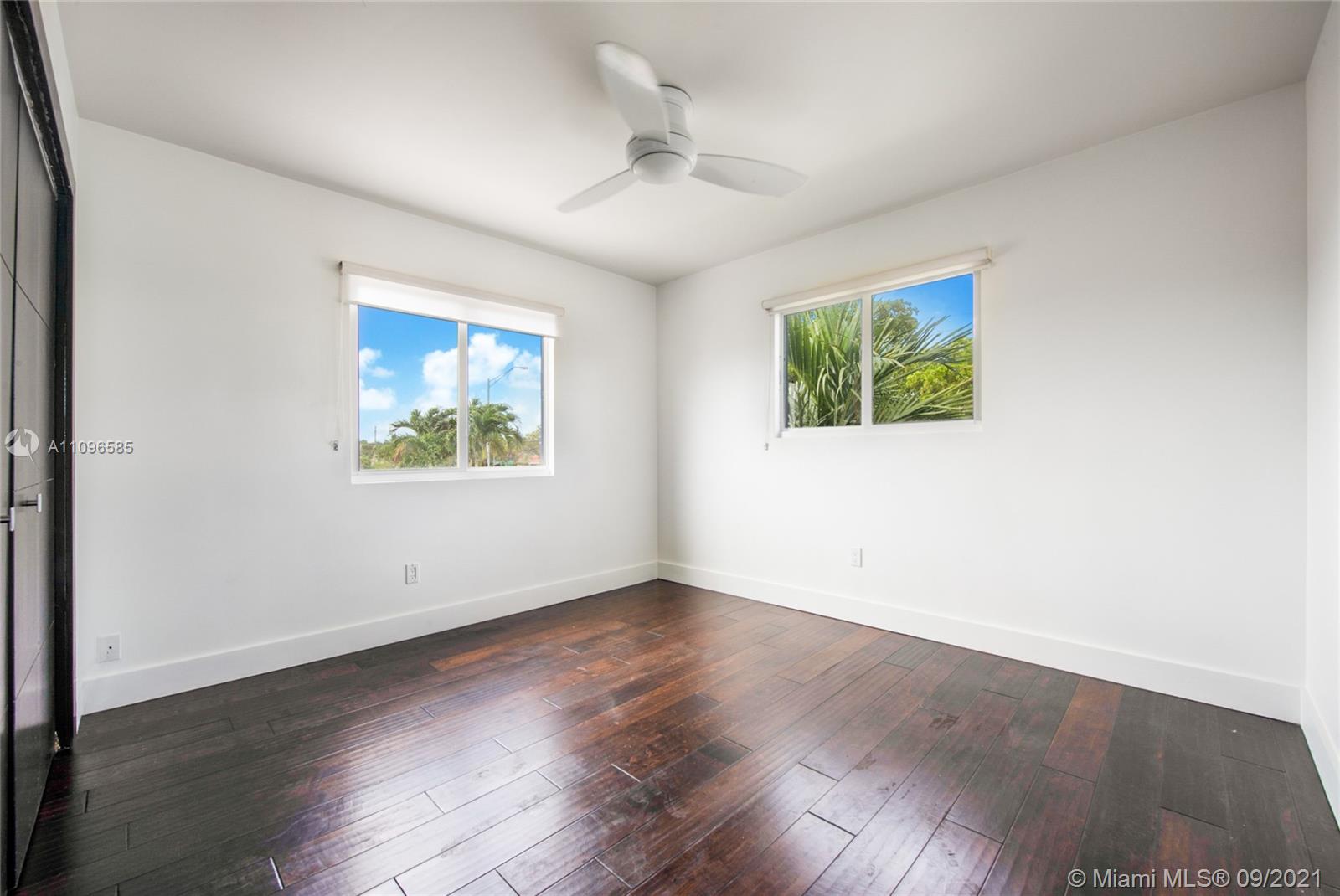 5131 Southwest 87th Avenue Miami, FL 33165 - Photo 16 of 24 an empty room with wooden floor ceiling fan and windows