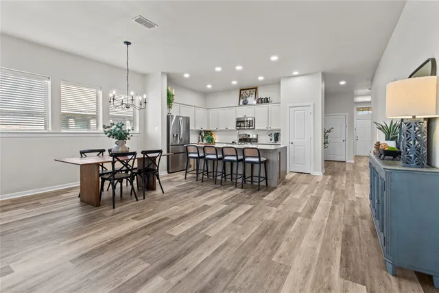 a living room with stainless steel appliances furniture wooden floor and a kitchen view