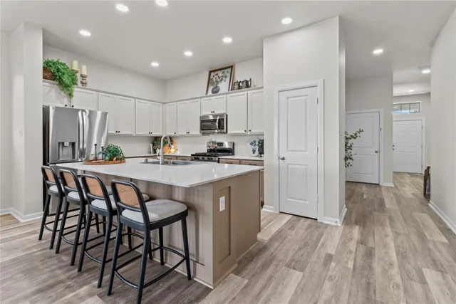 a kitchen with kitchen island granite countertop wooden floors and refrigerator