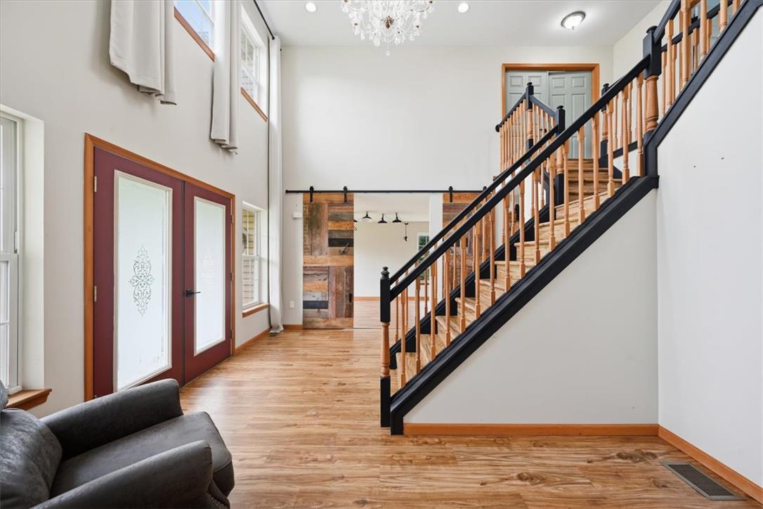 387 Blue Ridge Road Saylorsburg, PA 18353 - Photo 8 of 90 A grand entryway features high ceilings, elegant wood flooring, and a striking staircase with dark railings, creating a dramatic first impression.