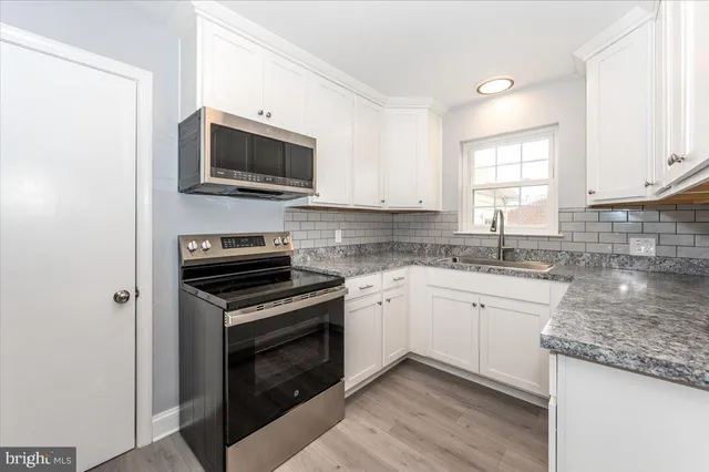 a kitchen with stainless steel appliances granite countertop a sink a stove a microwave and wooden cabinets