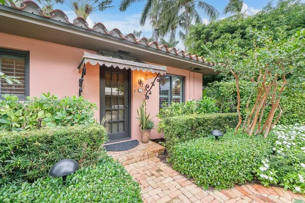 a front view of a house with a yard and potted plants
