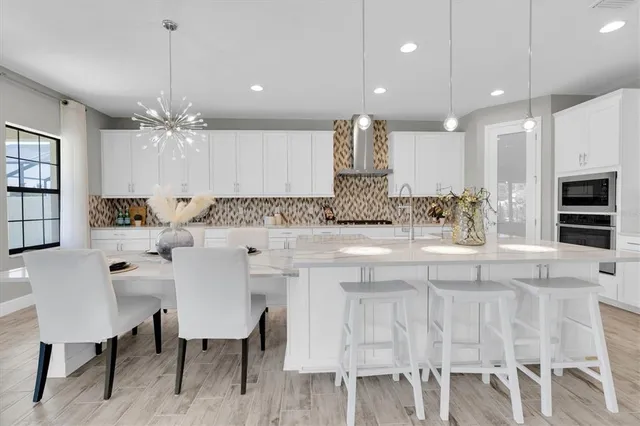 a kitchen with kitchen island granite countertop a stove a sink and white cabinets with wooden floor