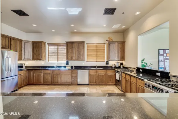 a large kitchen with granite countertop a large counter top space appliances and cabinets
