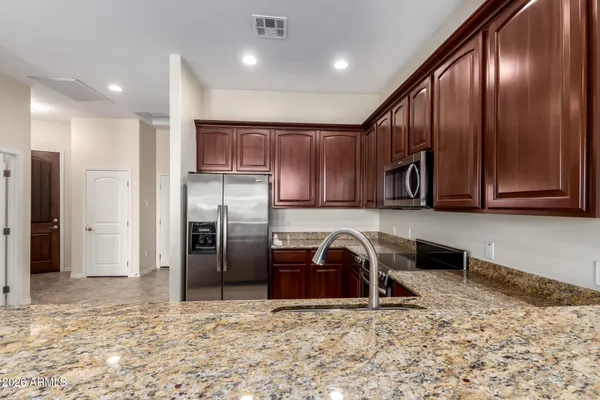 a kitchen with stainless steel appliances granite countertop a refrigerator a stove and a sink with wooden cabinets
