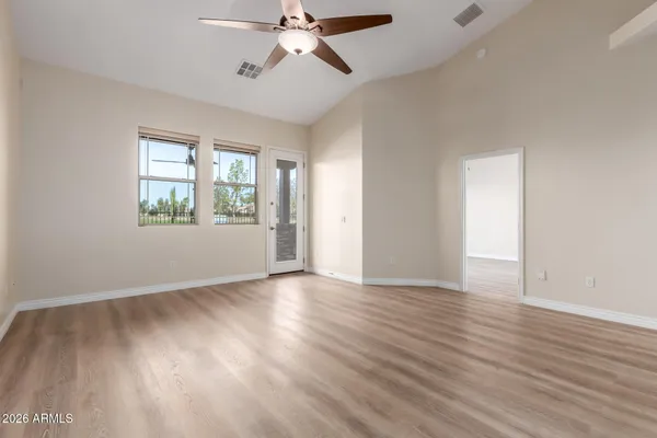 a view of an empty room with wooden floor and a window
