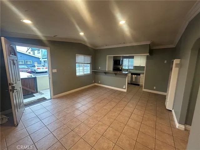 a view of empty room with kitchen and window