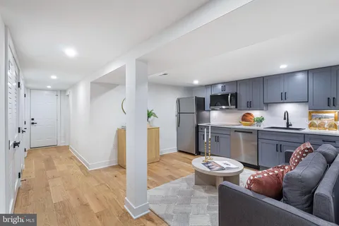 a living room with stainless steel appliances furniture a rug and a kitchen view