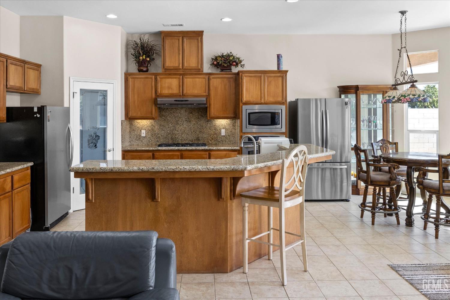 Undisclosed Address Bakersfield, CA 93312 - Photo 21 of 50 a kitchen with stainless steel appliances kitchen island granite countertop dining table chairs and a refrigerator