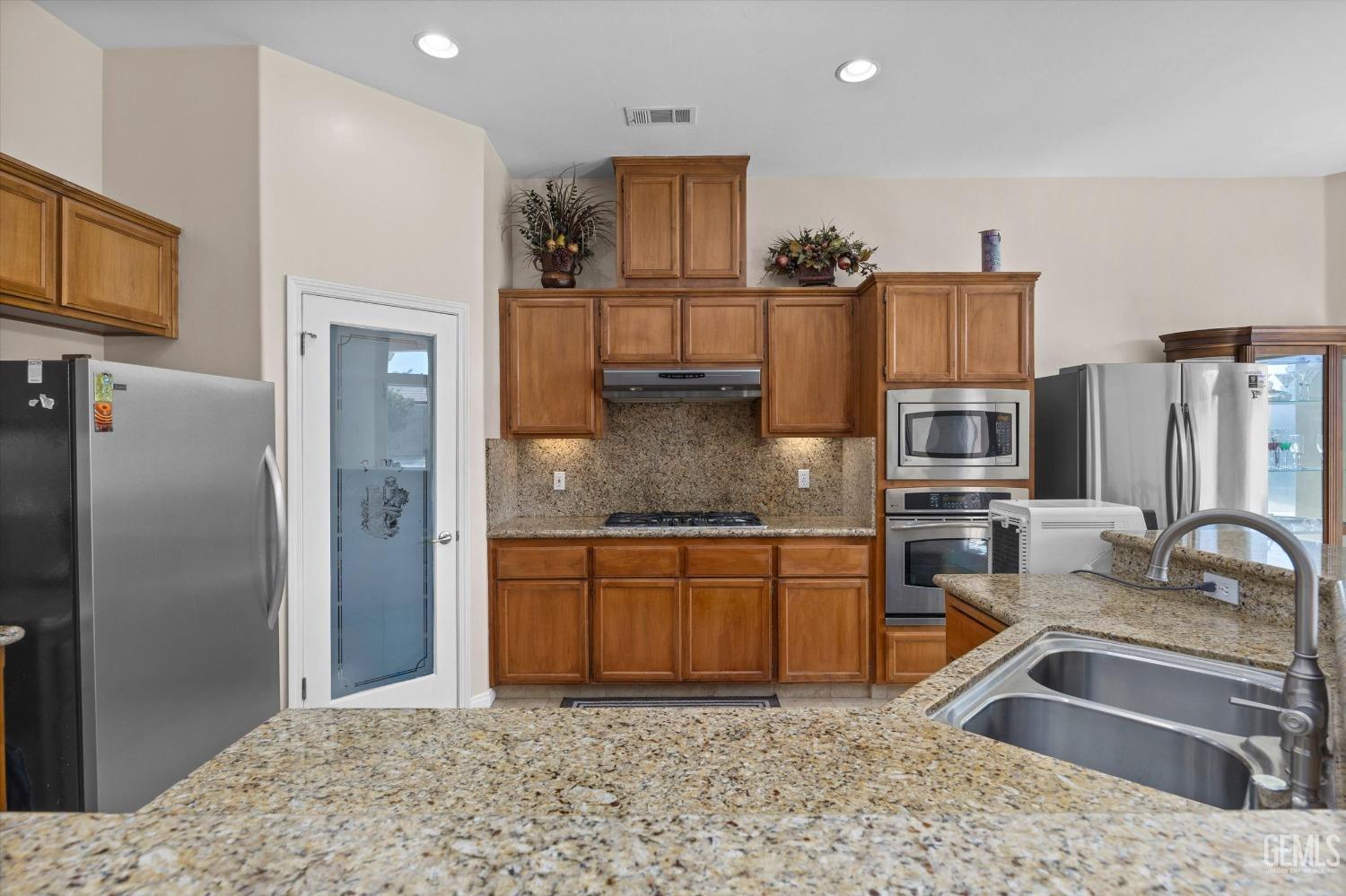 Undisclosed Address Bakersfield, CA 93312 - Photo 23 of 50 a kitchen with stainless steel appliances granite countertop a sink refrigerator and microwave