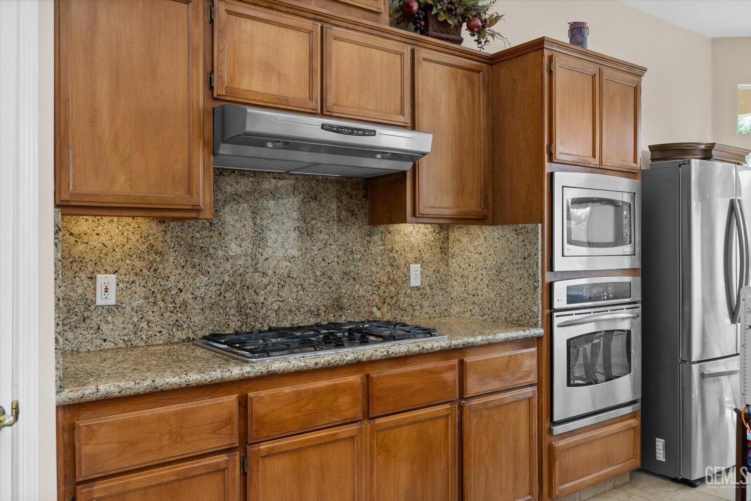 Undisclosed Address Bakersfield, CA 93312 - Photo 24 of 50 a kitchen with granite countertop a refrigerator stove and microwave
