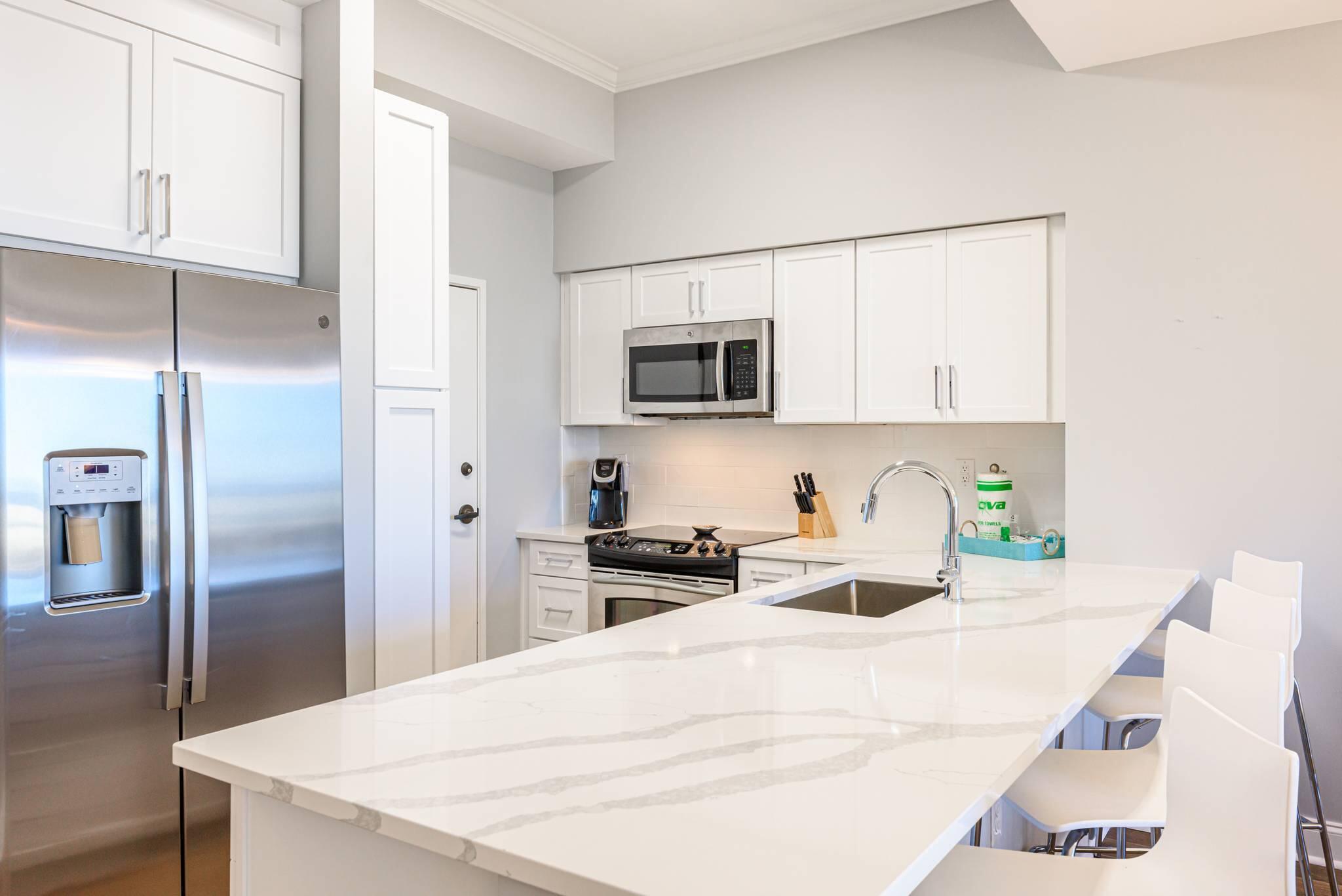 550 Tops'l Beach Boulevard, Unit 103 Miramar Beach, FL 32550 - Photo 4 of 20 a kitchen with a refrigerator a microwave a sink and cabinets