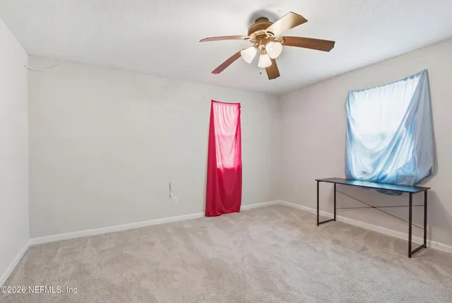 an empty room with windows and fan