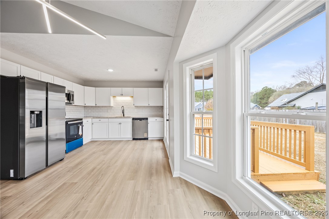 122 Tanner Loop Raeford, NC 28376 - Photo 10 of 36 a large white kitchen with wooden floor and a window