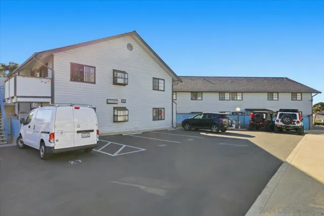 a view of a house with a yard and a car parked beside a road