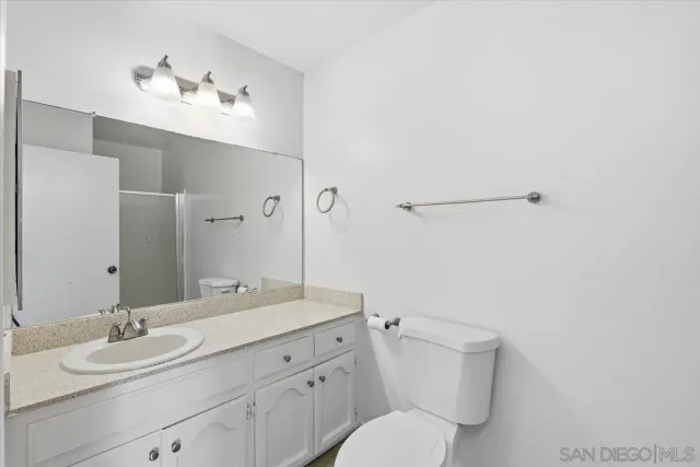a bathroom with a granite countertop sink a toilet and a large mirror