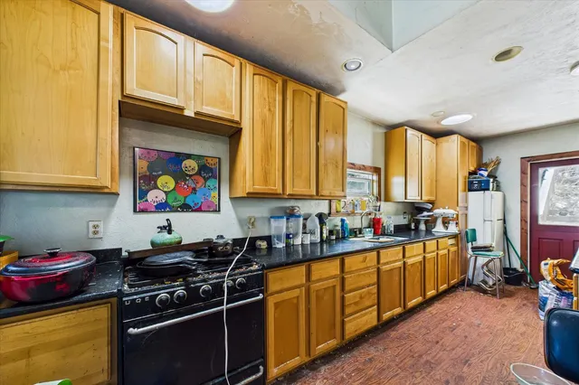 a kitchen with stainless steel appliances a stove a sink dishwasher and cabinets with wooden floor