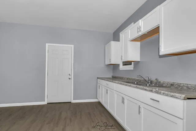 a kitchen with granite countertop white cabinets and a sink