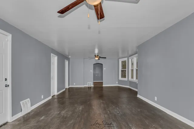 a view of an empty room with wooden floor and windows