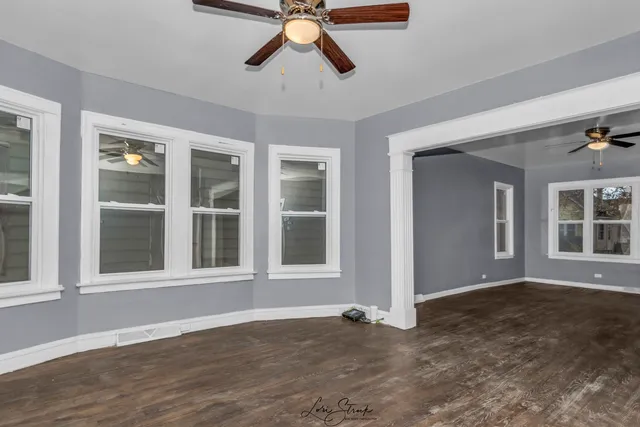 a view of an empty room with a window and wooden floor