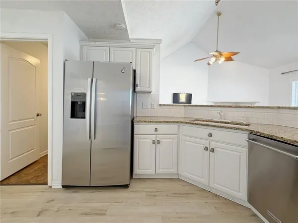 a kitchen with a chandelier stainless steel appliances cabinets and a counter space
