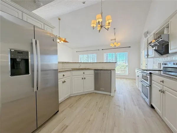 a kitchen with granite countertop a sink and a white wooden cabinets