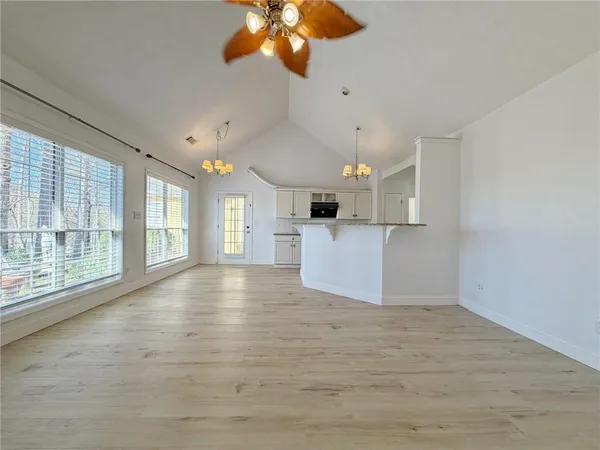 a view of an empty room with a window and wooden floor