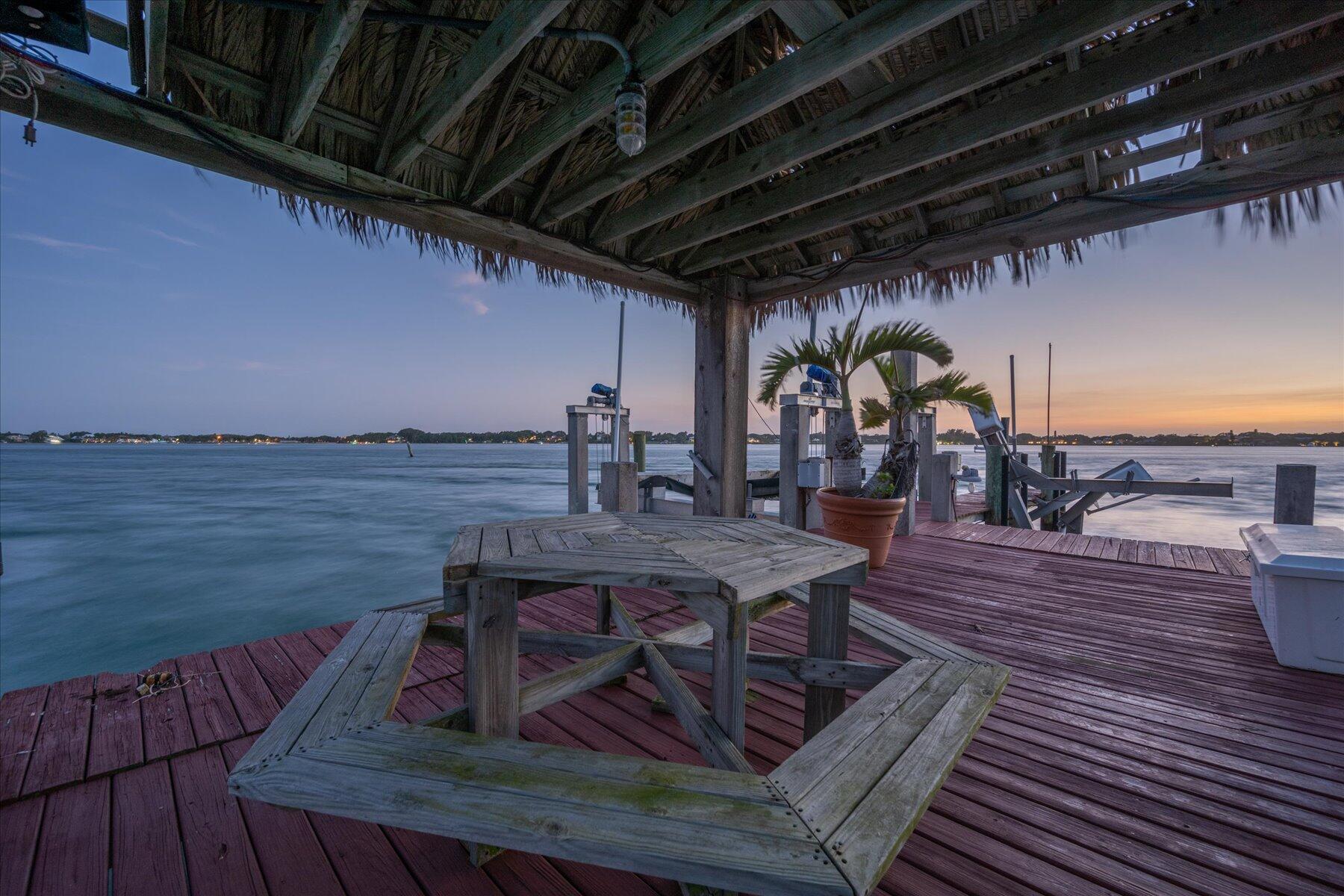 49 West High Point Road Sewall's Point, FL 34996 - Photo 85 of 99 a view of a roof deck with table and chairs a barbeque with wooden floor and plants