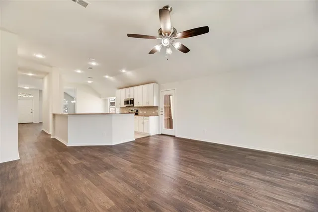 a view of kitchen with kitchen island stainless steel appliances wooden floor and living room view