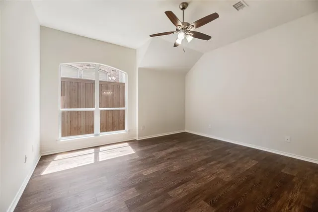 an empty room with wooden floor fan and windows