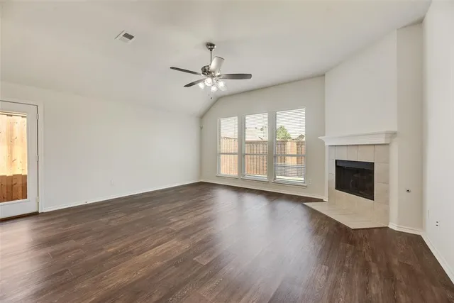 a view of an empty room with wooden floor fireplace and a window