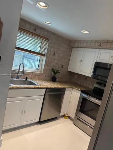 a kitchen with granite countertop white cabinets and stainless steel appliances