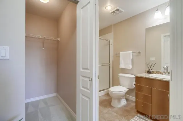 a bathroom with a granite countertop toilet a sink a mirror and a shower