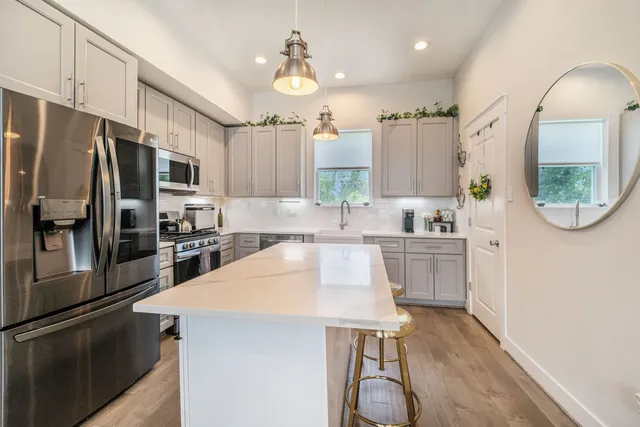 a kitchen with kitchen island a counter top space a sink stainless steel appliances and cabinets